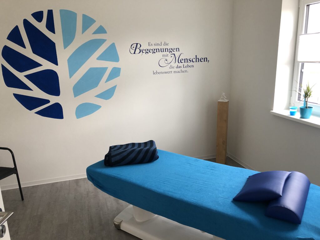 Heller Behandlungsraum mit blauer Therapieliege